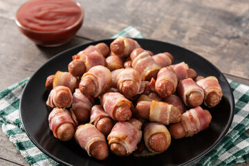 Pig in blankets. Sausages wrapped in smoked bacon on wooden table	