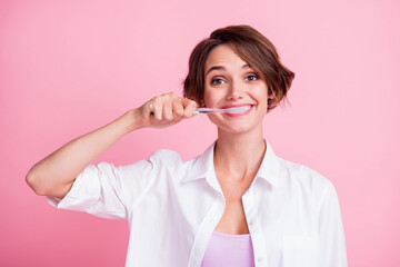 Photo of adorable cheerful young lady wear white shirt cleaning teeth toothbrush isolated pink color background