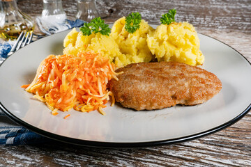 Minced meat cutlet served with mashed potatoes and carrot salad.