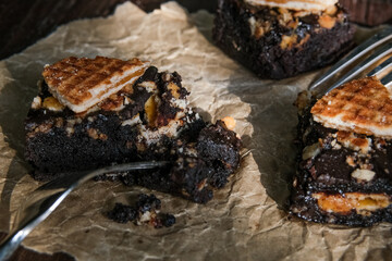 Brownies decorated with stroopwafel cookies on baking paper on top of wooden rustic background