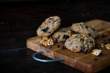 Chocolate chip cookies with walnuts on wooden chopping board background