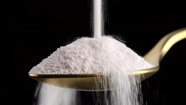 pour collagen powder in golden spoon on black background closeup. Natural beauty and health supplement