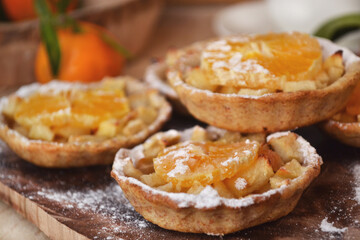 Mini fruit tarts with caramelized apple and tangerine. Homemade baking. Rustic style.
