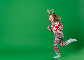 happy cheerful child girl in antlers deer with box in hands on green background