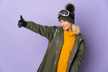 Skier Russian girl with snowboarding glasses isolated on purple background giving a thumbs up gesture