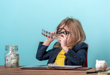 Child numismatist with metal coin in a transparent plastic protection square capsule. Kid with a magnifying glass is considering the old coin numismatist. Financial education. holder case