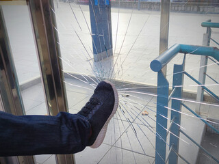 A violent male, boy, man, vandal,angry person breaks and destroys a window with a punch