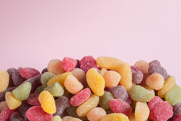 Lots of colorful sweets with sugar on illuminated pink background.