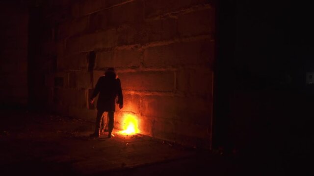 Two mans who heats near fire in massive cement building scared something.They intently looks in the dark to find something that agitate them
