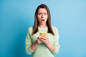 Photo portrait of upset woman holding yellow phone in two hands isolated on pastel blue colored...