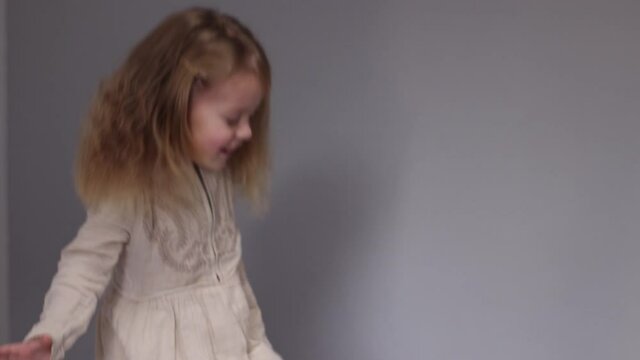 charming little girl having fun, jumping on bed in gray bedroom. morning routine, childhood, daughter. FullHD footage