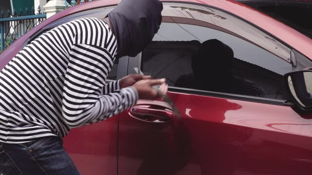 Thieves using metal steel feet pry car door lock . Robber man theft stealing property Finding a way to break the tire rim glass door from the outside. Car theft criminal concept.