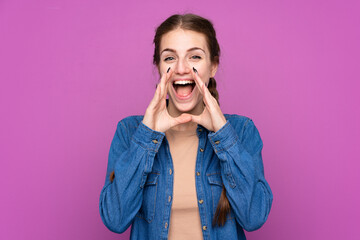 Young woman over isolated purple background shouting with mouth wide open