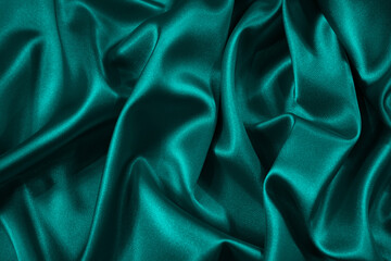 Blue green silk satin fabric. Teal color elegant background. Liquid wave or silk wavy folds....