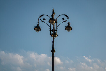 Beautiful minimalistic photo of a vintage lantern on a blue clear sky with small clouds during the day