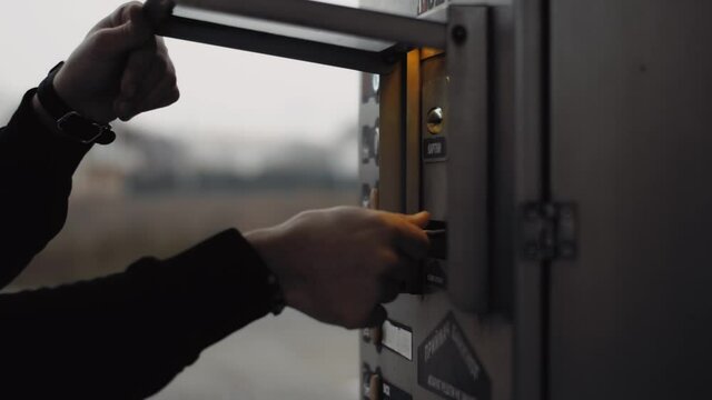 Man on self-service carwash open a cover of bill acceptor and gives a cash for a using