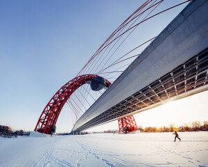 Zhivopisny Bridge Moscow winter. Unique view from under the bridge. Only accessible in winter when the Moscow River is frozen. Wide panorama sunny day. Silhouette of the skying man on the background
