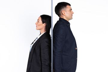 Young people, serious businesswoman and businessman being, back to back to a wall on a white background.