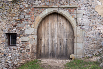 Fototapeta na wymiar Old wooden medieval door in stone wall