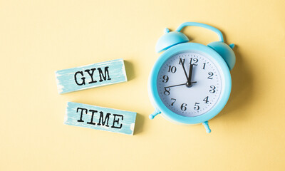Wooden block with text Gym Time with alarm clock.