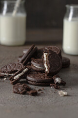 Sandwich biscuits cookies filling with vanilla cream and glass of milk on dark background for breakfast concept
