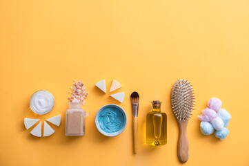 Fototapeta na wymiar Face cream, Himalayan salt, facial mask, brush, olive oil, hairbrush and cotton wool on yellow background. Natural vegan cruelty free organic cosmetic products on yellow background with copy space
