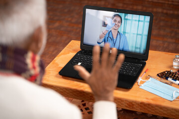 Shoulder shot of Old man on video with to doctor on laptop screen - concept of Online Chat,...