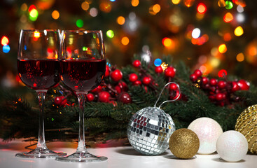 Glasses of wine and Christmas balls on the background of Christmas lights