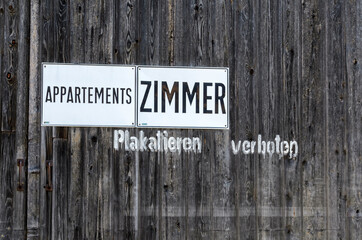 Weathered  wooden wall with the inscription "No bill-sticking!" and advertising for apartements