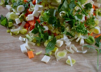 Traditional vegetables and herbs for a soup in Bavaria,Germany,diced cut on a wooden board, blurred dark background, carrots, celery, leek, parsley, lovage, advertising for cuisine, copy space