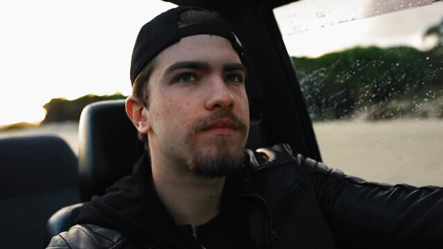 Giovane ragazzo con cappello nero guida una macchina