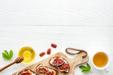 Sandwiches with cheese, fresh figs and walnuts on wooden cutting board