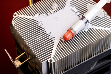 Fototapeta premium thermal paste at syringe package over dark red gradient background. copy space. studio shot. thermally paste for computer hardware
