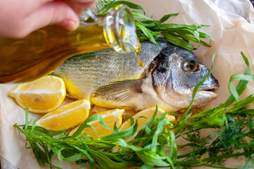 Dorada with lemon and fresh herbs, the chef pours oil on the fish before baking