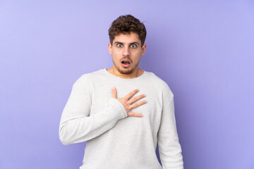 Caucasian man isolated on purple background surprised and shocked while looking right