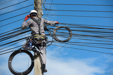 Electricians carry radio walkie talkie communications on poles to maintain high-voltage lines on dangerous electric towers. Wear full safety harnesses.