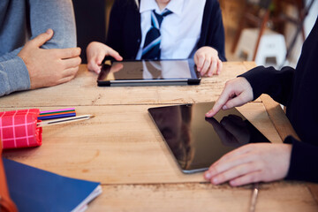 Close Up Of Father Helping Children Using Digital Tablets Wearing School Uniform With Homework