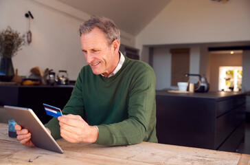 Fototapeta premium Senior Man At Home Buying Products Or Services Online Using Digital Tablet And Credit Card