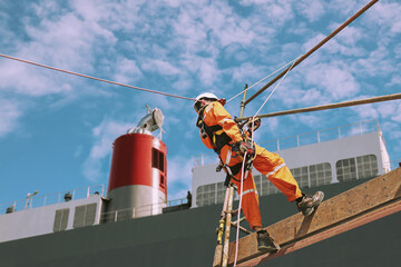 Rope access and abseiling worker on high wear dresses and safety man with harness concept on steel structures success from work in site construction on blue sky background.