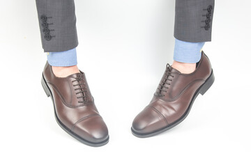 Classic brown leather shoes worn on the hands on a white background