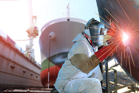 Welder is Welding process Ship repair with spark light building ship in dock yard background wear equipment protective in shipyard.