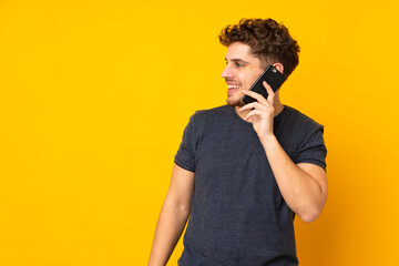 Young caucasian man isolated background keeping a conversation with the mobile phone with someone