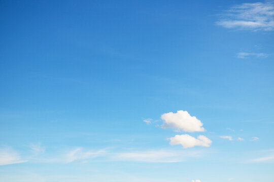 Small, fluffy and lonely clouds in the blue sky with copy space for texture background