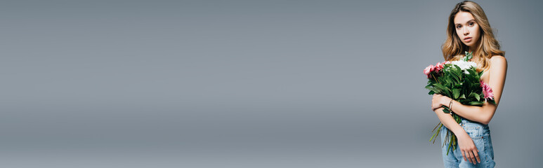 sensual young woman with naked shoulders holding bouquet isolated on grey, banner