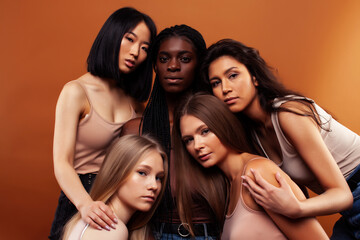 Obraz premium young pretty asian, caucasian, afro woman posing cheerful together on brown background, lifestyle diverse nationality people concept