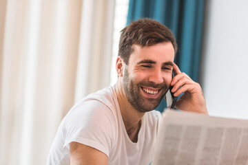 Photo of busy businessman working from home, talking on the phone with colleague and looking at document papers.