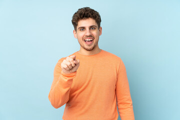 Caucasian man isolated on blue background surprised and pointing front