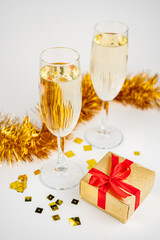 Two glasses with champagne and gold gift box on white background
