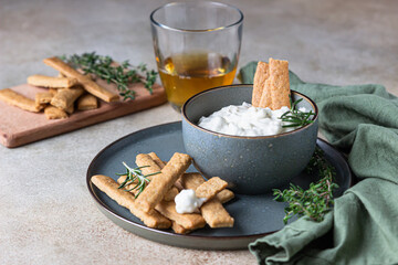 Blue cheese dressing or dip sauce with rosemary and gingerbread cookies sticks on concrete background.