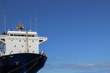 Naklejka premium Container ship mooring in port and accommodation deck or captain cabin, antenna, captain on blue sky background.